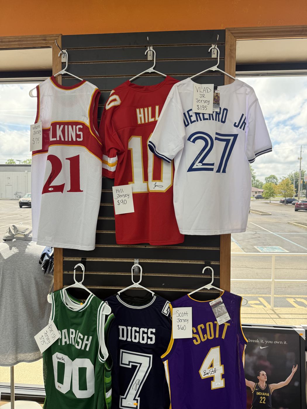 Autographed jerseys hanging on the wall with handwritten price tags